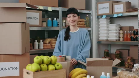Lasdy smiling on camera while packing food at charitable fund Stock Footage 173597182