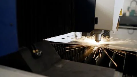 Laser cutting machine processing metal sheet, creating sparks and embers Stock Photos