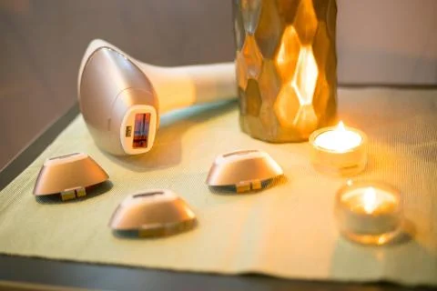 Laser epilator on table with three extensions and two candles Stock Photos