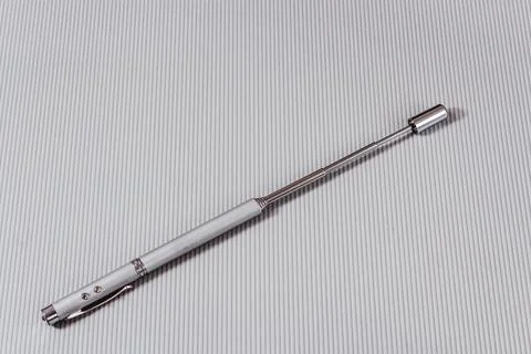 Laser pointer in the form of a telescopic stationery pen on a light backgroun Stock Photos