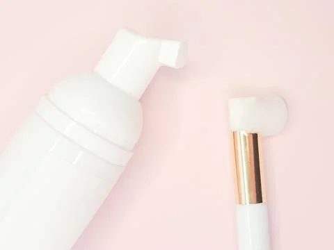 Lash shampoo bottle with applicator on soft pink background for beauty concep Stock Photos