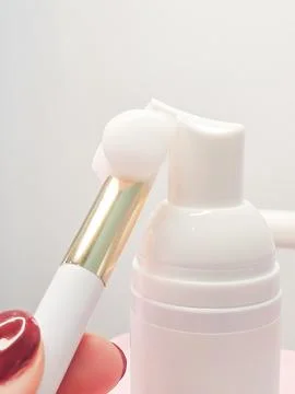 Lash shampoo concept with applicator brush and white bottle on soft backgroun Stock Photos
