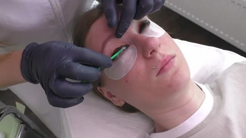 Lashmaker Applies Serum on Eyelashes of Client For Eyelash Lamination Treatment Stock Footage 274573054