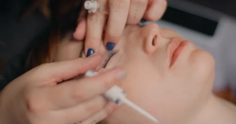 Lashmaker does the eyelash lamination procedure for the client in the beauty Stock Footage 246325217