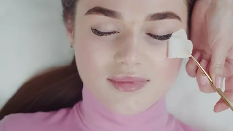 Lashmaker takes a patch from under the eyelashes young woman with gold tweezers Stock Footage 194172038