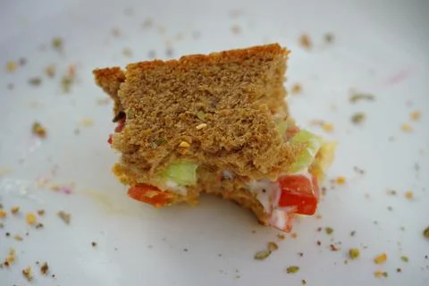 Last bite of a vegetable sandwich kept on plate. Side view shot of bread with Stock Photos