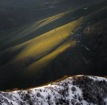 The last light of the day illuminates the path that leads to a snowy mountain Stock Photos