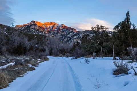 Last light on orange cliffs above snowed in trail into Utah desert wilderness Stock Photos