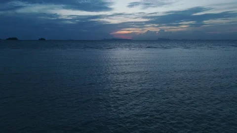 Last light touching distant horizon. Calm ocean reflecting vibrant hues of Stock Footage 312743677