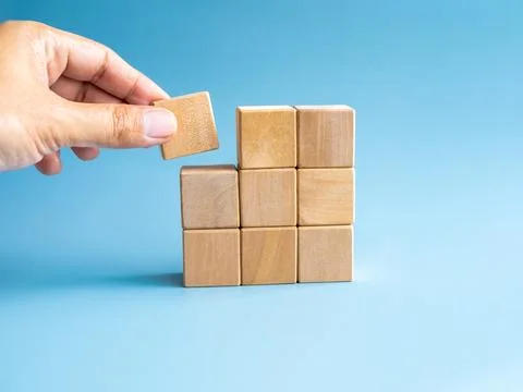 Last piece wood cube block in hand putting on wooden puzzles stacking arran.. Stock Photos