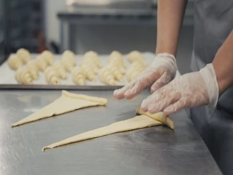 Last preparation before baking. Baker glazing croissants with egg wash working Stock Footage
