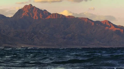 Last sun rays on the top of mountain and sea waves in foreground Stock Footage 341300906