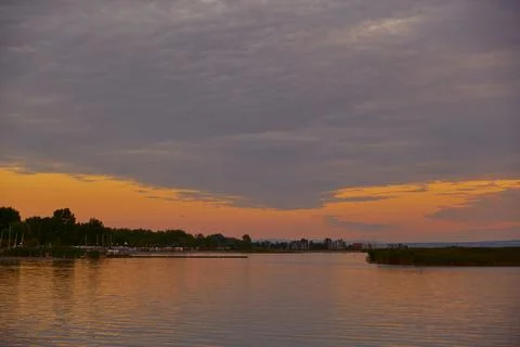 Last sunset rays over lake with patterned sky and distant shoreline Foto stock