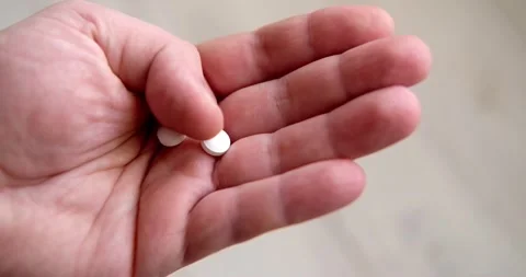 The last two pills fall from the can into the man's palm. Medicine, addiction Stock Footage 146742390