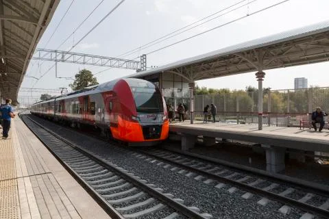 The "Lastochka" train pulls up to the passenger platform Stock Photos