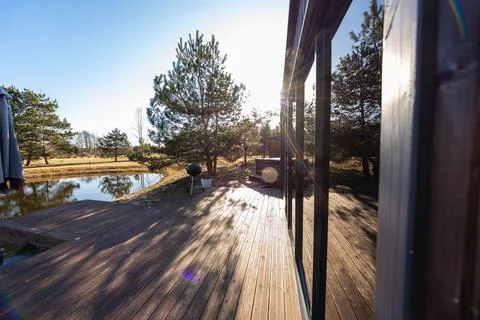 Late afternoon light on deck by reflective pond and modern cabin Stock Photos