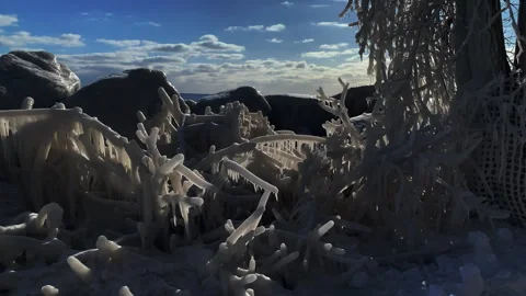 Late afternoon sun shining through natural ice formations created by extreme Stock Footage 332086165