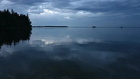 Late blue hour view of a calm peaceful northern lake with trees on shore  Stock Footage 300894742
