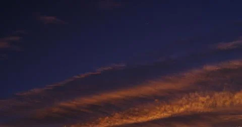 Late-day clouds, set ablaze by the setting sun, with a crescent sickle moon. Fotos Stock