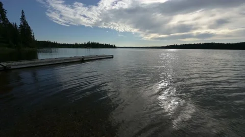 Late day sun is reflecting in a with small waves and a dock in the foreground  Stock Footage 161119485