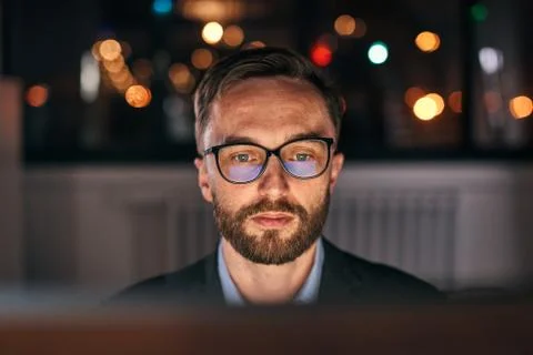 Late night working under a project looking at the computer screen. Stock Photos