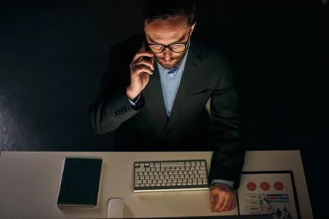 Late night working under a project looking at the computer screen. Stock Photos