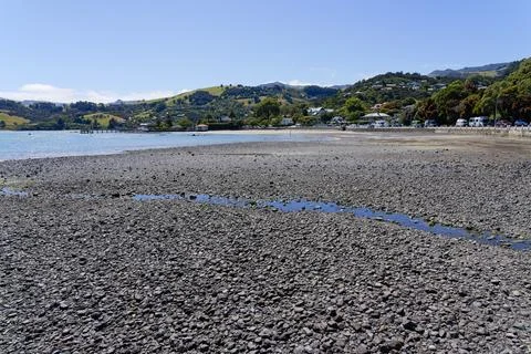 Late summer on empty stony beach in Akaroa, Canterbury, New Zealand Stock Photos
