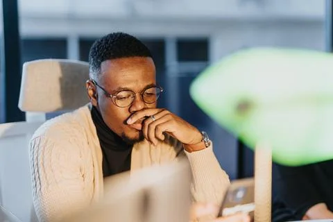 Late at work, the employee solves task problems, determined to find solutions. Stock Photos