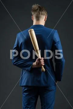 Latent aggression. Businessman or man in formal suit hides wooden bat behind Stock Photos