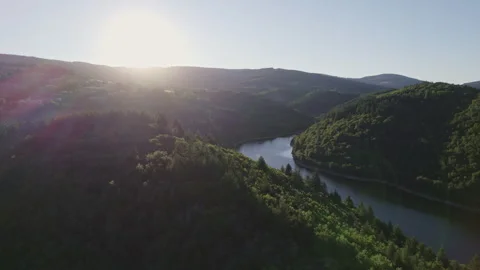 Lateral Aerial View of Lake Between Green Forested Mountains in Dazzling Light Stock Footage 315617636