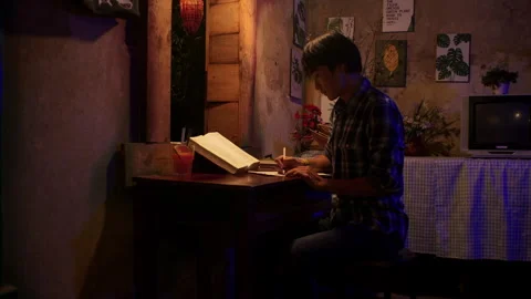 Lateral close up view of a young asian man copying a text from a night Stock Footage 241470263