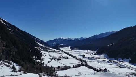 Lateral Drone Flight Over Snowy Maiern Village with Alpine Mountains in Stock Footage 332164898