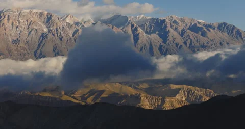 Lateral drone shot of dramatic clouds drifting past rugged peaks in Mustang Видео 335433646