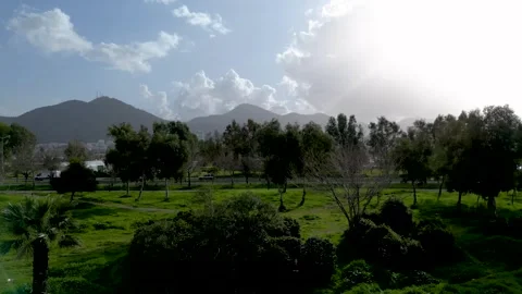 Lateral Drone Shot of Green Park, Road, and Sunlit Mountains Stock Footage 321014765