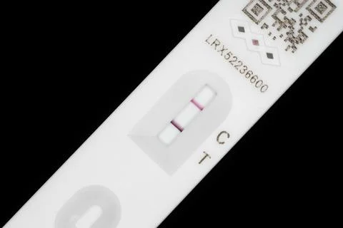 A lateral flow test strip close-up, showing a positive test result. Foto stock