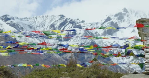 Lateral shot of vibrant and fluttering Buddhist prayer flags in the snowy Stock Footage 336341029
