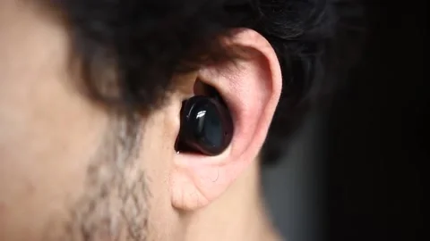 A lateral view from a bearded man putting a wireless headphone on his ear   Stock-Footage 218641648