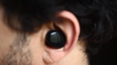 A lateral view from a bearded man struggling to put a wireless headphone on his  Stock Footage 218641660