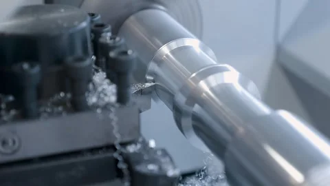A lathe cutter processes a shiny metal part and the chips fall into a receiver Stock Footage 333344635