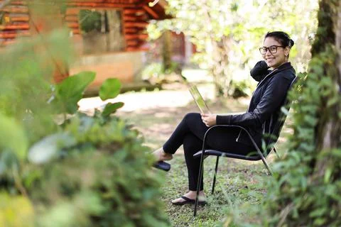 Latin American Woman Looking Camera Smiling working with laptop in the forest Fotos de archivo