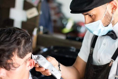 Latin barber using face mask, using a razor on client. Hair Stimulation growth Stock Photos