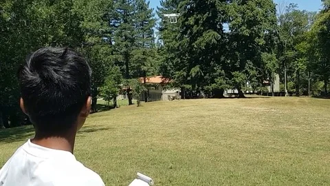 Latin boy operating a drone with remote control. Quadro copter drone flying over Vídeos de archivo 97938552