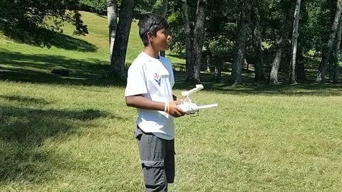 Latin boy operating a drone with remote control. Quadro copter drone flying over Vidéo 97938565