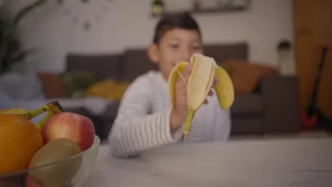 Latin boy snacking fruit sitting at table in living room at home. Healthy Video stock 244596962