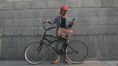 Latin cyclist using his phone with a bicycle outdoors. Urban mobility. Stock Footage 290161675
