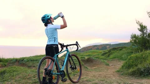 Latin cyclist woman drinking and riding gravel bike by the sea at sunrise Stock Footage 309817853
