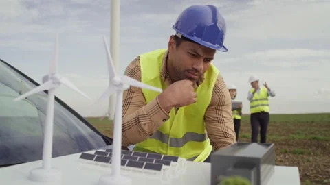 Latin engineers thinking over the project of field with windmill Stock-Footage 221223678