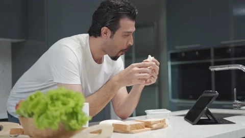 Latin handsome man eating bread with tuna and looking and finger touching scr Stock Footage 168621190