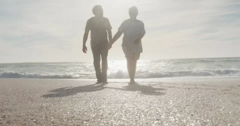 Latin hispanic couple holding hands, walking on beach at sunset Stock Footage 335568257