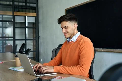 Latin Indian young programmer student sitting using laptop at modern office. Stock-Fotos